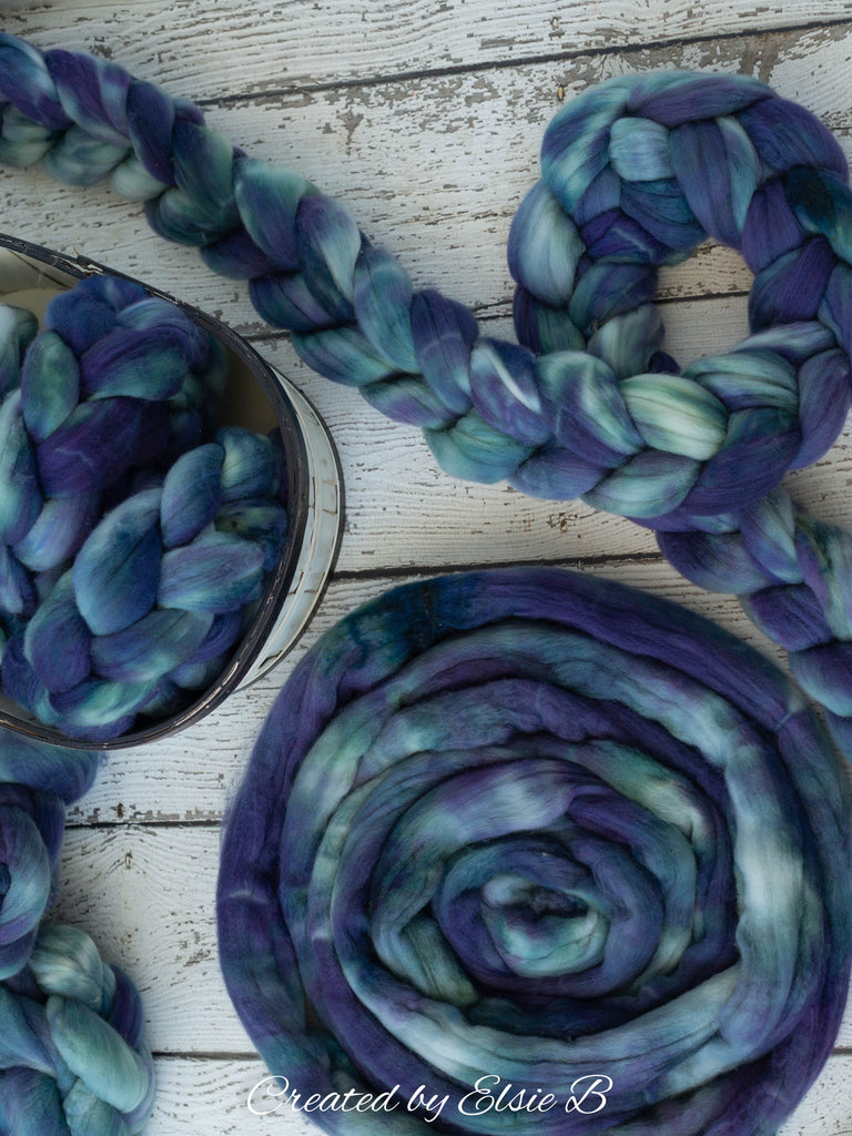 Blue and purple semi solid hand dyed wool on a white wooden backdrop