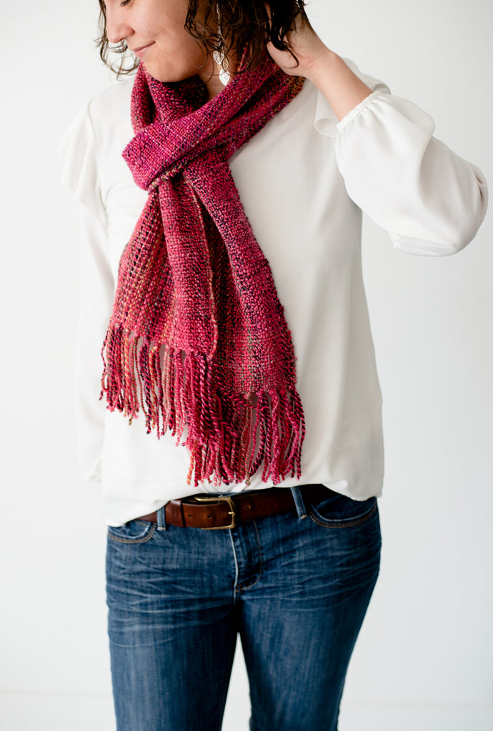 Scarf around a brown haired woman's neck, pink and red with hints of black, brown and green